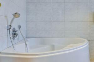 Un baño con bañera blanca y un inodoro. en Katharinenhof Ferienwohnung Kramer Groß (3), en Garmisch-Partenkirchen