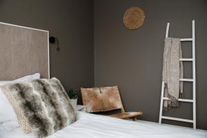 ein Schlafzimmer mit einem Bett mit einer Decke und einem Stuhl in der Unterkunft Hotel Aan Zee in Noordwijk aan Zee