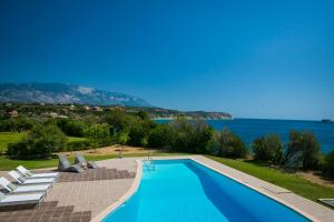 - une piscine avec des chaises et une vue sur l'eau dans l'établissement Villa Gaia, à Svoronata