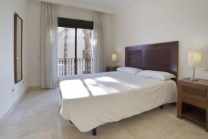 1 dormitorio con 1 cama blanca grande y balcón en La Roza de Roda Golf en San Javier