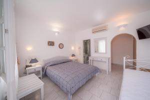 a white bedroom with a bed and two tables at Vardia Bay Studios in Karavostasi
