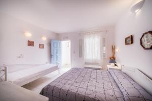 a white bedroom with a large bed and a window at Vardia Bay Studios in Karavostasi