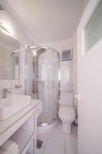 a white bathroom with a toilet and a shower at Vardia Bay Studios in Karavostasi