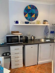 um balcão de cozinha com um micro-ondas e um lavatório em Bungalow by the sea near Cape Town em Kleinmond