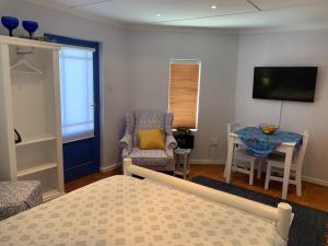 a bedroom with a bed and a chair and a table at Bungalow by the sea near Cape Town in Kleinmond
