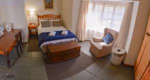 a bedroom with a bed and a desk and a chair at Buller's Rest Guest Lodge in Ladysmith