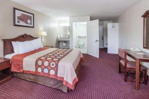 a hotel room with a large bed and a desk at Super 8 by Wyndham Clinton in Clinton