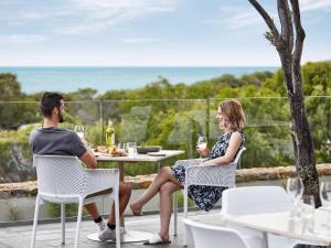 
a woman and a boy sitting at a picnic table at Pullman Bunker Bay Resort Margaret River in Dunsborough
