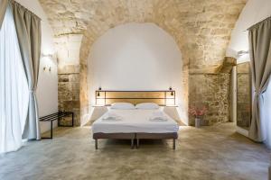 Scicli Albergo Diffuso في شيكلي: غرفة نوم بسرير في جدار حجري