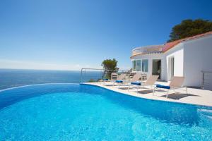 a swimming pool with chairs and a house at Sueño Azul in Jávea