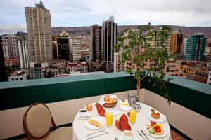a table with food on a balcony with a view of a city at Camino Real Aparthotel, Downtown in La Paz
