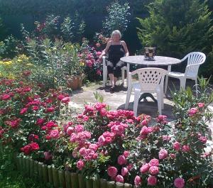 una mujer sentada en una mesa en un jardín con rosas en Brigitta vendégház, en Egerszalók