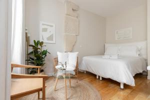 a white bedroom with a bed and a glass table at Appartement Vertus in Paris