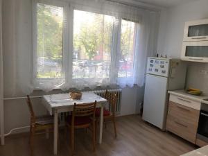 a kitchen with a table and chairs and two windows at Sunny appartment by the river in Dolný Kubín