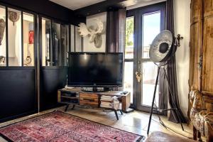 ein Wohnzimmer mit einem Flachbild-TV und einem Ventilator in der Unterkunft Le clos des Anges in Cogolin