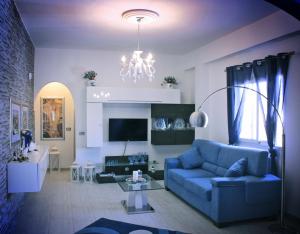 een woonkamer met een blauwe bank en een kroonluchter bij Timone Luxury in Gela