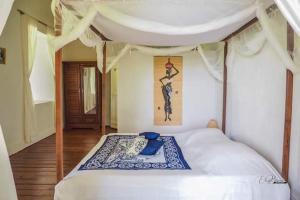 a bedroom with a white bed with a painting on the wall at Lambawany in Sainte Marie +48 photos
