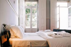 two beds in a room with two windows at Dona Emília Guest House & Studio Apartments in Viana do Castelo