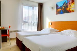 a hotel room with two beds and a window at Cerise Strasbourg in Strasbourg