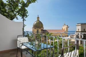 a balcony with a glass table and a view of the city at Hotel Palazzo Murat in Positano