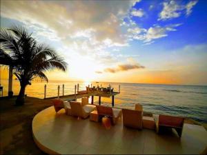 a sunset on the beach with chairs and a pier at Down South 118 Beach Resort in Oslob