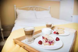 a tray with two plates of food and a drink on a bed at Domek w Dąbrowie in Wielogłowy