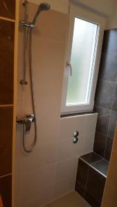 La salle de bains est pourvue d'une douche et d'une fenêtre. dans l'établissement Apartman Darja, à Umag