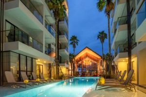 a hotel swimming pool with lounge chairs and palm trees at Surin Beach Residence in Surin Beach