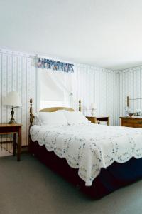 een slaapkamer met een bed met een witte deken en een raam bij Carriage Barn Inn in Keene