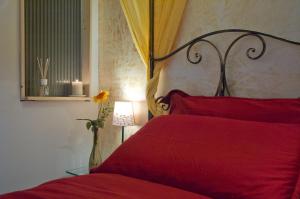 a bedroom with a red bed and a vase with a flower at Light of Rome in Rome