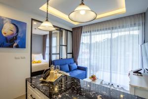 a hotel room with a blue chair and a bedroom at Surin Beach Residence in Surin Beach