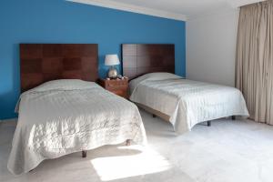 Loft Sabalo - Pet Friendly في مازاتلان: سريرين في غرفة نوم بحائط ازرق