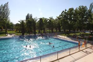 a large swimming pool with people in the water at Hostal - Bungalows Camping Cáceres in Cáceres