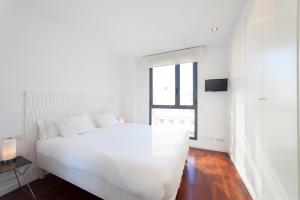 biała sypialnia z białym łóżkiem i oknem w obiekcie Ático Valencia Centro w Walencji
