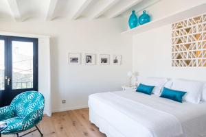 a white bedroom with a large bed and a chair at Boutique Hotel Villa Gala by Fimedhotels in Cadaqués