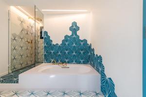 a bathroom with a tub with blue and white tiles at Boutique Hotel Villa Gala in Cadaqués