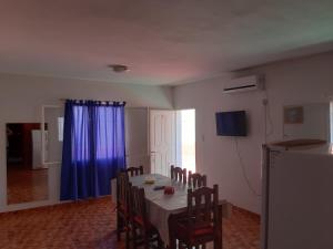 een eetkamer met een tafel met stoelen en een blauw gordijn bij Apart Hotel Del Sol in Chilecito