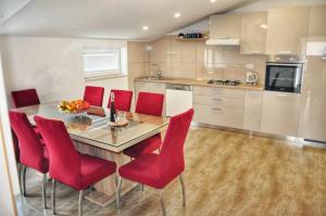 eine Küche mit einem Holztisch und roten Stühlen in der Unterkunft Apartman Đoni in Split