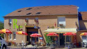 un restaurante con mesas y sombrillas frente a él en Relais Du Lac en Villegusien Le Lac