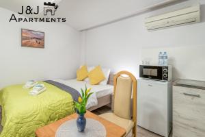 Kleines Zimmer mit einem Bett, einem Tisch und einer Mikrowelle. in der Unterkunft J&J Apartments, Łazienna 30 Apartament 8/2 in Toruń