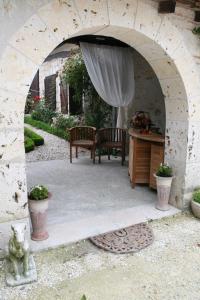a stone archway with a table and chairs in a yard at Chambres Rozies Dunes in Dunes