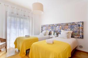 - une chambre avec 2 lits avec des draps jaunes dans l'établissement Gorgeous Beach Apartment - Checkinhome, à Carcavelos