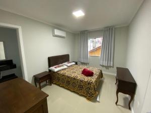 a bedroom with a bed and a chair and a window at Edifício Florenza in Bombinhas