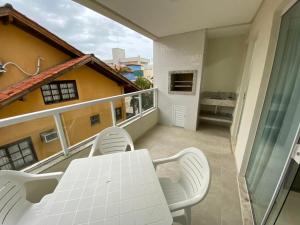 un balcón con una mesa blanca y sillas. en Edifício Florenza, en Bombinhas