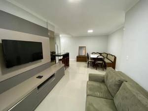 a living room with a couch and a flat screen tv at Edifício Florenza in Bombinhas