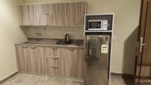 a kitchen with a stainless steel refrigerator and a microwave at Rose Niry Hotel Suites روز نيري للاجنحة الفندقية in Al Khobar