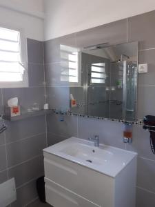 La salle de bains blanche est pourvue d'un lavabo et d'un miroir. dans l'établissement Sol'Caribea Samara, à Sainte-Anne