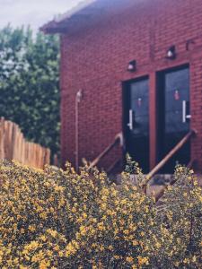 a red brick building with two doors and yellow flowers at Solanas de Uspallata in Uspallata