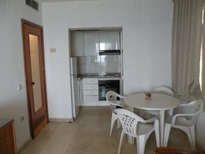 een witte tafel en stoelen in een kamer met een keuken bij Torre Levante - Fincas Arena in Benidorm