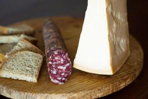 a wooden cutting board with cheese and a sausage and bread at Bed & Breakfast Torrechiara in Torrechiara +11 photos